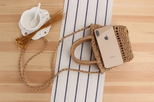 Flat lay of a woven straw beach bag with dual handles and straps on a wooden table