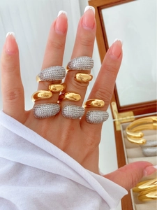 Close-up of stacked gold and silver drop rings with cubic zirconia on a model's finger