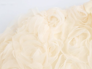 Detailed macro shot of 3D mesh rose floral fabric on a sweet style beige cardigan