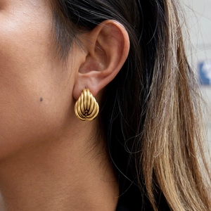 Gros plan de boucles d'oreilles cœur dorées en acier inoxydable sur une oreille