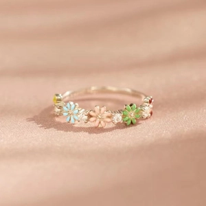 Floral silver ring with colorful enamel petals and zircon accents on pink silk fabric