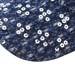 Detailed macro view of dark blue denim fabric with silver sequins and distressed fringe detail