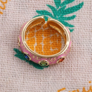 Detail of adjustable gold-plated ring with pink enamel and colorful inset gemstones