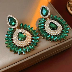 Macro view of geometric teardrop earrings with green rhinestones and silver pins