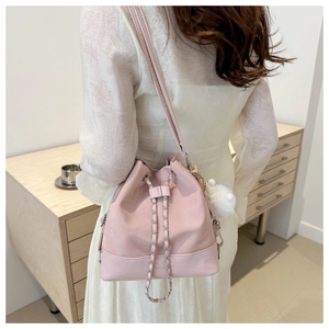 Pink PU leather bucket bag with chain drawstring and pompom charm on a model back