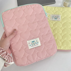 Close-up of quilted heart patterns on pink and yellow laptop sleeve with happy labels