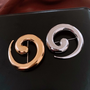 Macro detail of gold and silver spiral metal brooches on a premium black leather texture