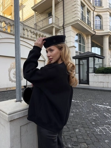 Detail of black street style sweatshirt and wool beret against a European city background