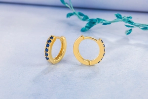 Detail of 14K gold hoop earrings featuring a single row of sparkling blue gemstones