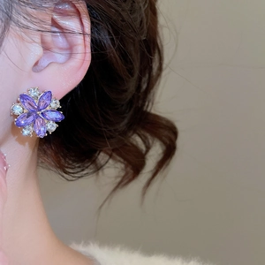 Detail of purple flower crystal earrings with sparkling white diamonds on a model