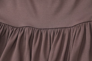Détail des coutures plissées et de la texture d'une robe moulante marron d'été