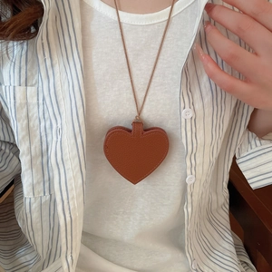 Detail of dark brown leather heart pendant necklace styled on a casual outfit