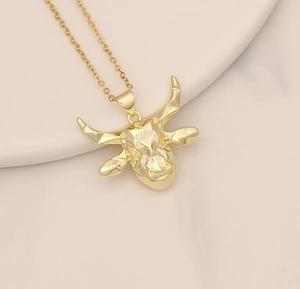 Detail shot of a golden bull head pendant with micro-set cubic zirconia on a fine chain