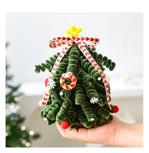 Handheld view of a DIY green pipe cleaner mini Christmas tree with small balls and bows