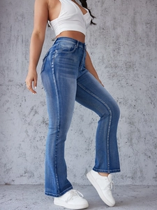 Detail of high waisted flared jeans in vintage washed blue with distressed stitching
