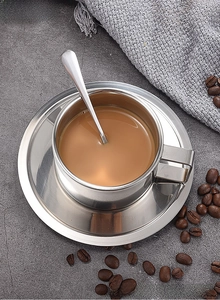 Polished stainless steel coffee cup set with saucer and spoon on a stone surface