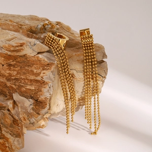 Detail shot of golden tassel earrings with beaded chains on a natural rock display