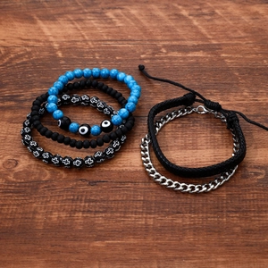 Hip hop beaded bracelet set with evil eye and cross charms on dark wood background