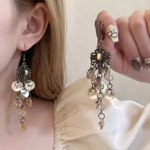 Gros plan de boucles d'oreilles vintage en bronze avec glands bohèmes portées par mannequin