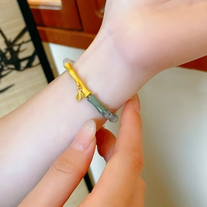 Detailed shot of bamboo-style gold bracelet with green and grey jade beads on wrist
