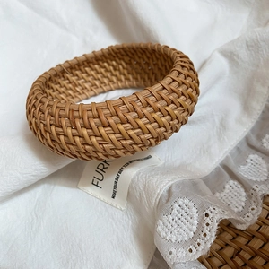 Gros plan d'un large bracelet en rotin tressé à la main au style bohème vintage