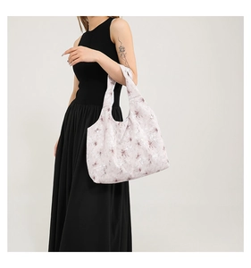 Detail of large tote bag with floral print styled by a model in a black dress
