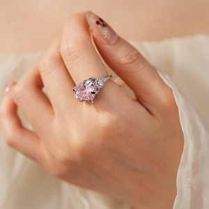 Close-up of heart shaped pink stone ring with zircon star crown detail on finger