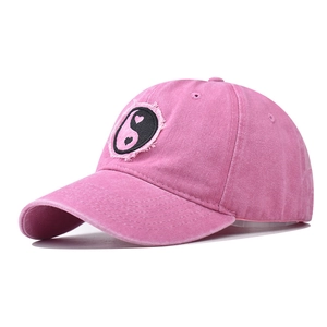 Dettaglio del cappellino in cotone lavato rosa con toppa ricamata yin-yang a cuore