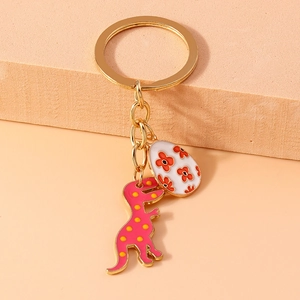 Pink dinosaur with yellow spots and floral egg keychain in golden metal finish