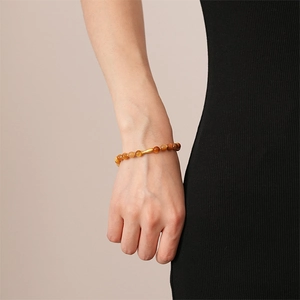 Detail of beaded tiger eye bracelet with a gold cylinder bead on a model's wrist