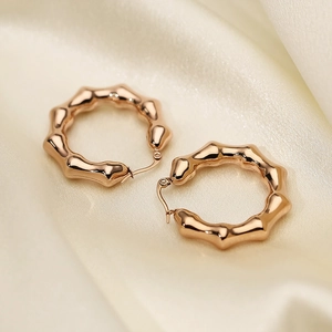 U-shaped bamboo design hoop earrings in rose gold finish on silk background