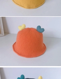 Macro detail of hand-knitted orange bucket hat with colorful heart-shaped ornaments