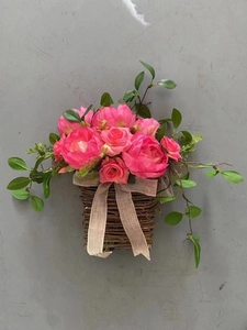 Detail of pink rose and peony hanging basket with rustic burlap bow on grey wall