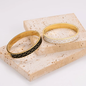 Enamel checkered gold plated stainless steel bangles on travertine stone display
