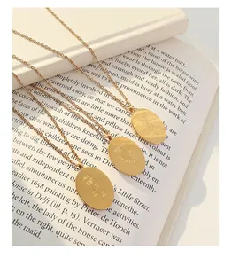 Detail of three gold oval necklaces with engraved floral patterns on an art book
