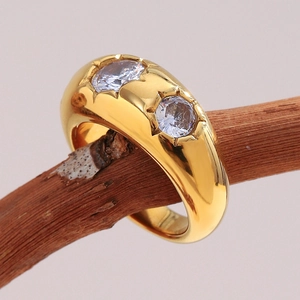Close-up of wide gold-plated stainless steel ring with two zircons on a wooden branch