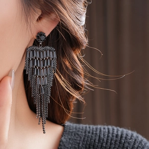 Close-up of black long tassel earrings with sparkling rhinestones on female model