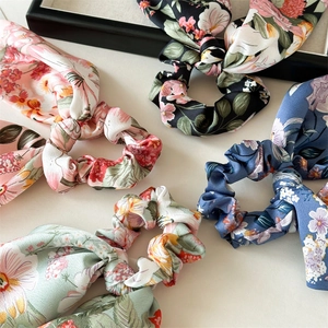 Detailed view of assorted floral satin scrunchies in pink, blue, and mint green colors