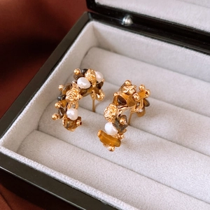 Macro shot of 18K gold plated tiger eye stone earrings with pearl floral detail