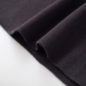 Close-up of soft dark knit fabric with belt detail on an elegant autumn midi dress