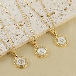 Gold stainless steel shell necklaces with crystal letters B, C, and G on silk background