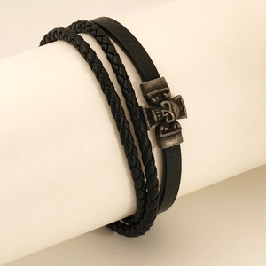 Macro detail of multi-layer black leather bracelet with vintage silver skull cross charm