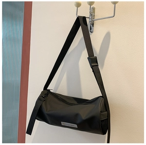 Détail d'un sac bandoulière cylindrique en nylon noir imperméable avec poche filet