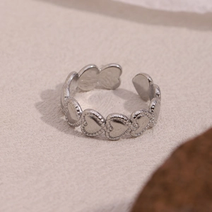 Macro shot of silver open ring featuring a continuous heart design with beaded texture details