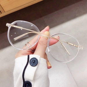 Retro-Rundbrille mit transparentem Rahmen und goldenen Metallbügeln in der Hand