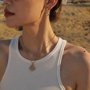 Détail du collier boho en or 18 carats avec pendentif œil bleu et boucles d'oreilles
