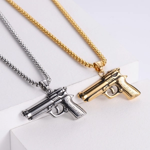 Detail of retro stainless steel pistol pendants in gold and silver finishes on stone