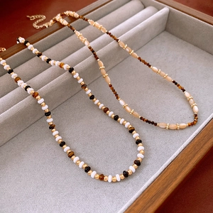 Detail of beaded flower necklaces with faux tiger eye stones in a grey jewelry tray