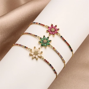 Three elegant gold flower bracelets with colorful zircon stones on white display stands