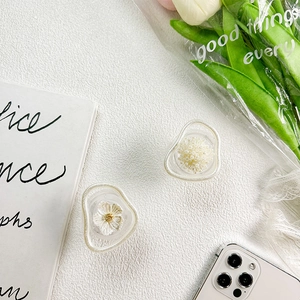Macro detail of irregular flower and pearl bead resin phone grip on a white background